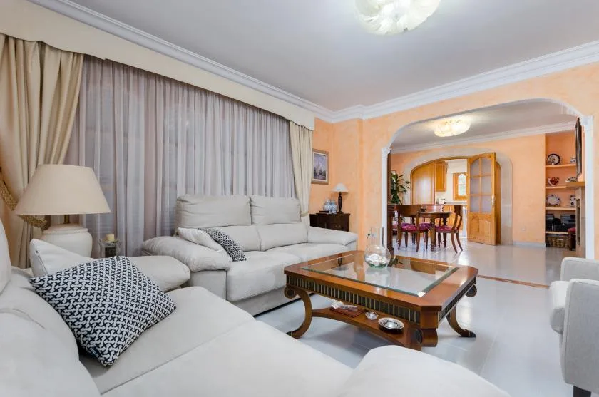 A living room with light-colored seating and a glass-topped coffee table.