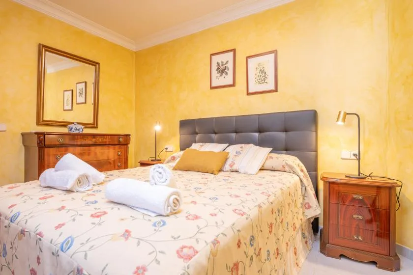 A bedroom with a large bed, bedside tables, and warm yellow walls.