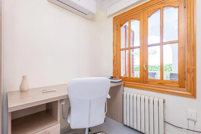 A bright desk area sits beside a large wooden-framed window.
