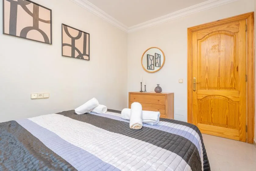 A bedroom with a bed, folded towels, and a wooden door.