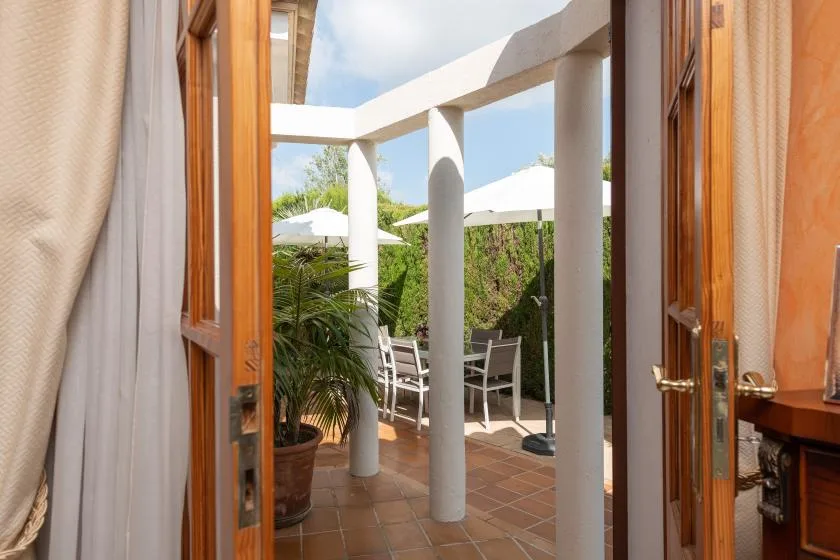 A patio with outdoor seating, umbrellas, and potted greenery.