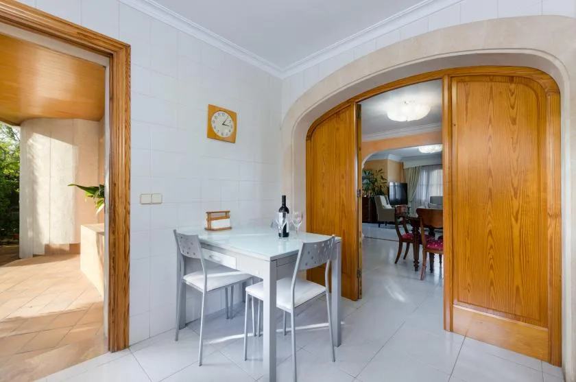 A small dining area with a white table and chairs beside wooden doors.