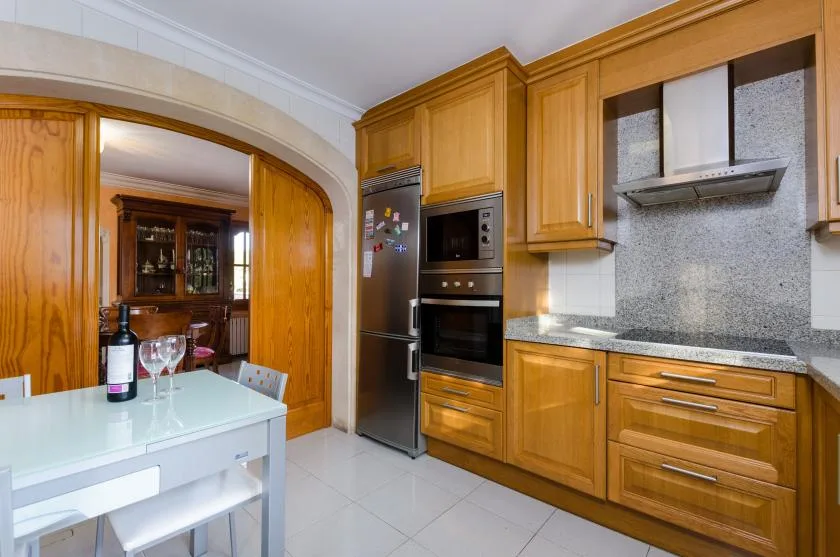 A fitted kitchen with wooden cabinets, built-in appliances, and a counter.