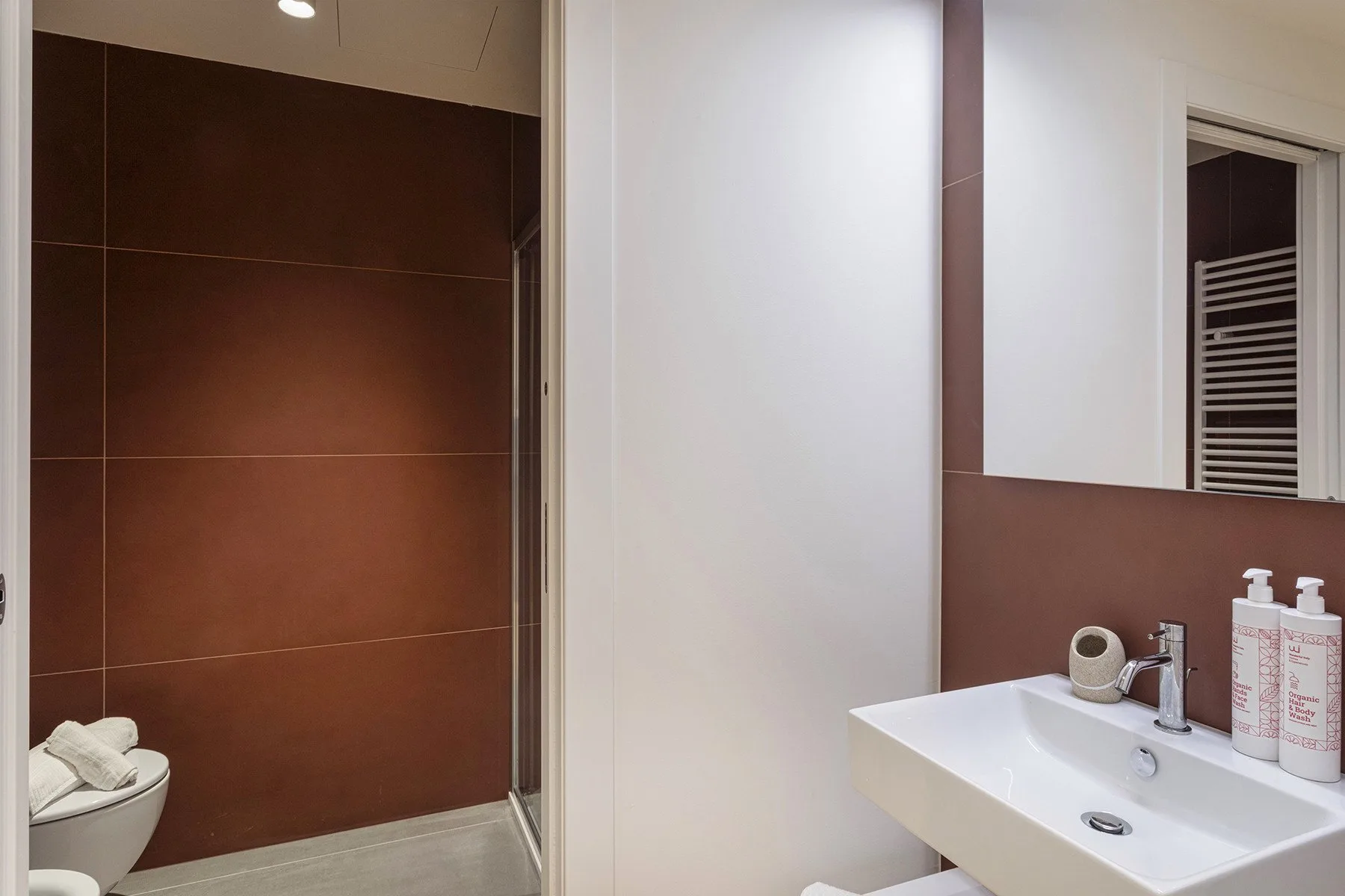 A modern bathroom with a white sink and a tiled shower area.
