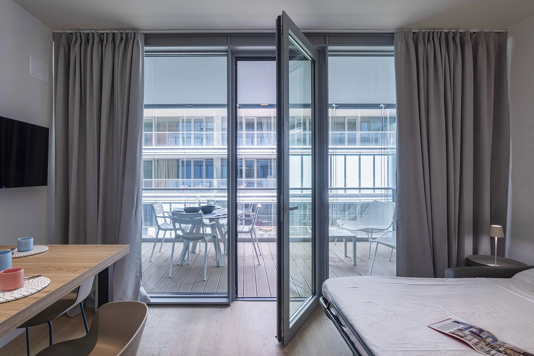 A bedroom with a bed, curtains, and glass doors opening onto a balcony.