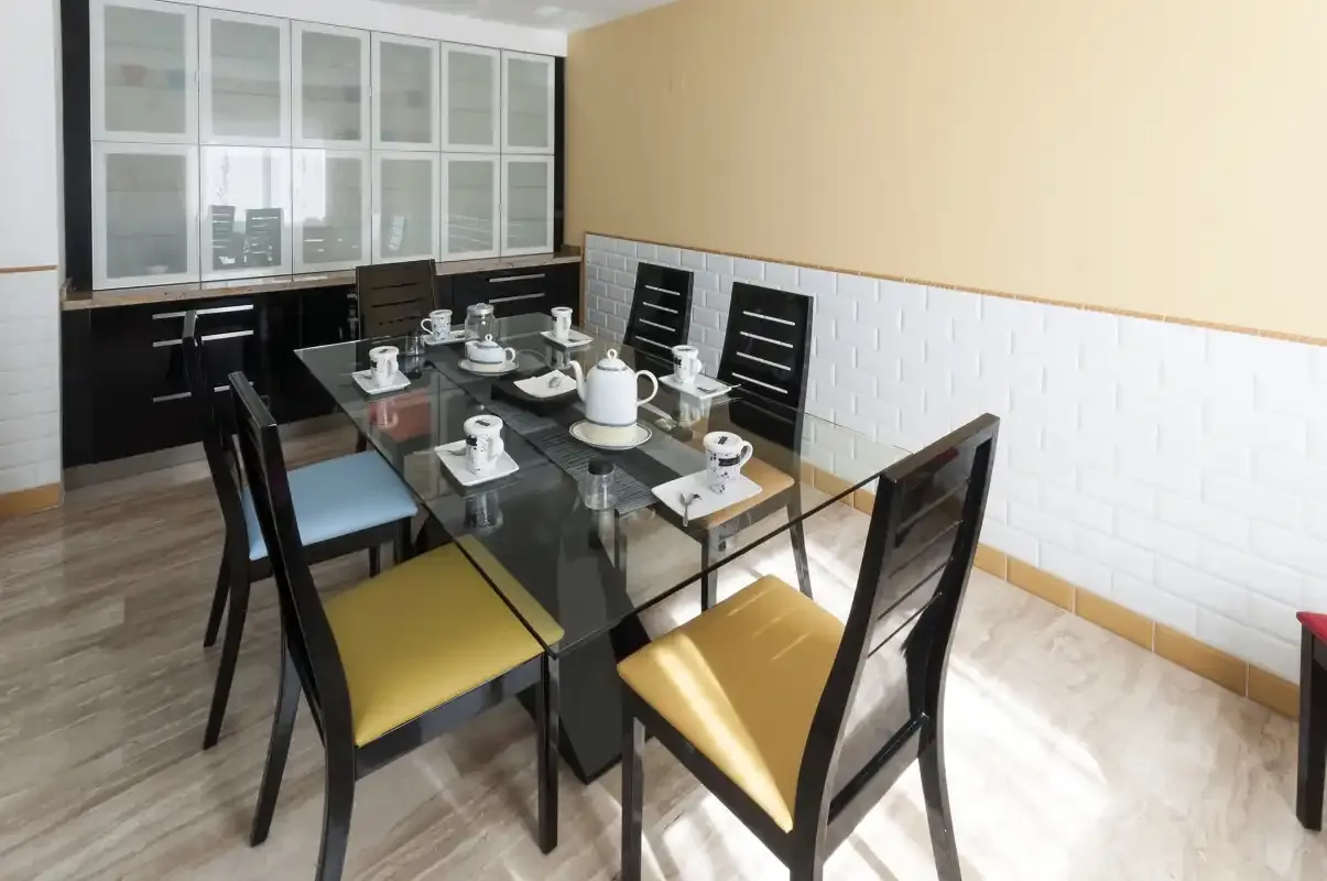Comedor con una mesa de vidrio y asientos negros.