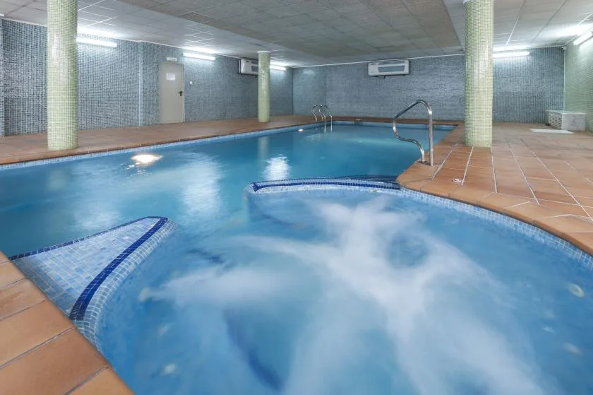 An indoor swimming pool with tiled walls and a surrounding deck.