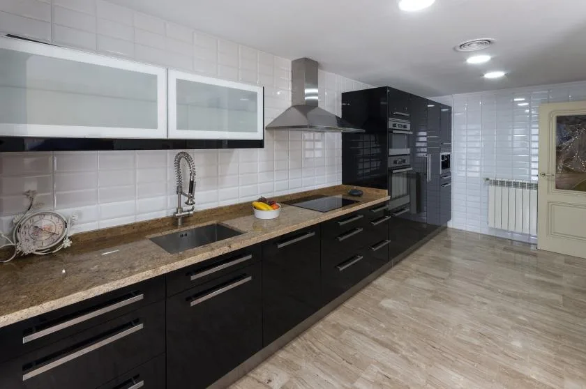 Una cocina moderna con gabinetes oscuros, una encimera larga y electrodomésticos integrados.