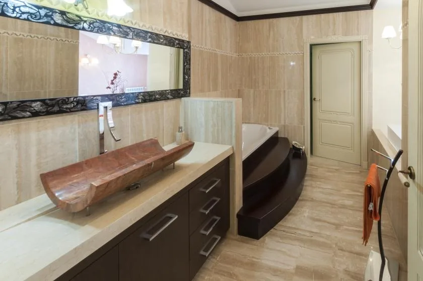 Un baño con un tocador largo, un espejo de pared y una bañera.