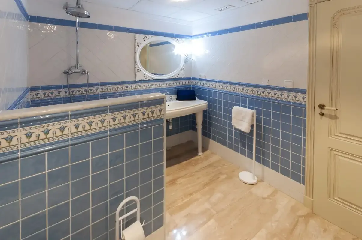 Un baño alicatado con lavabo, espejo y ducha.