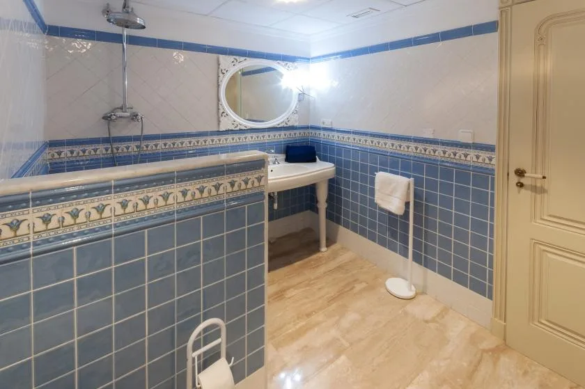 Un baño alicatado con lavabo, espejo y ducha.