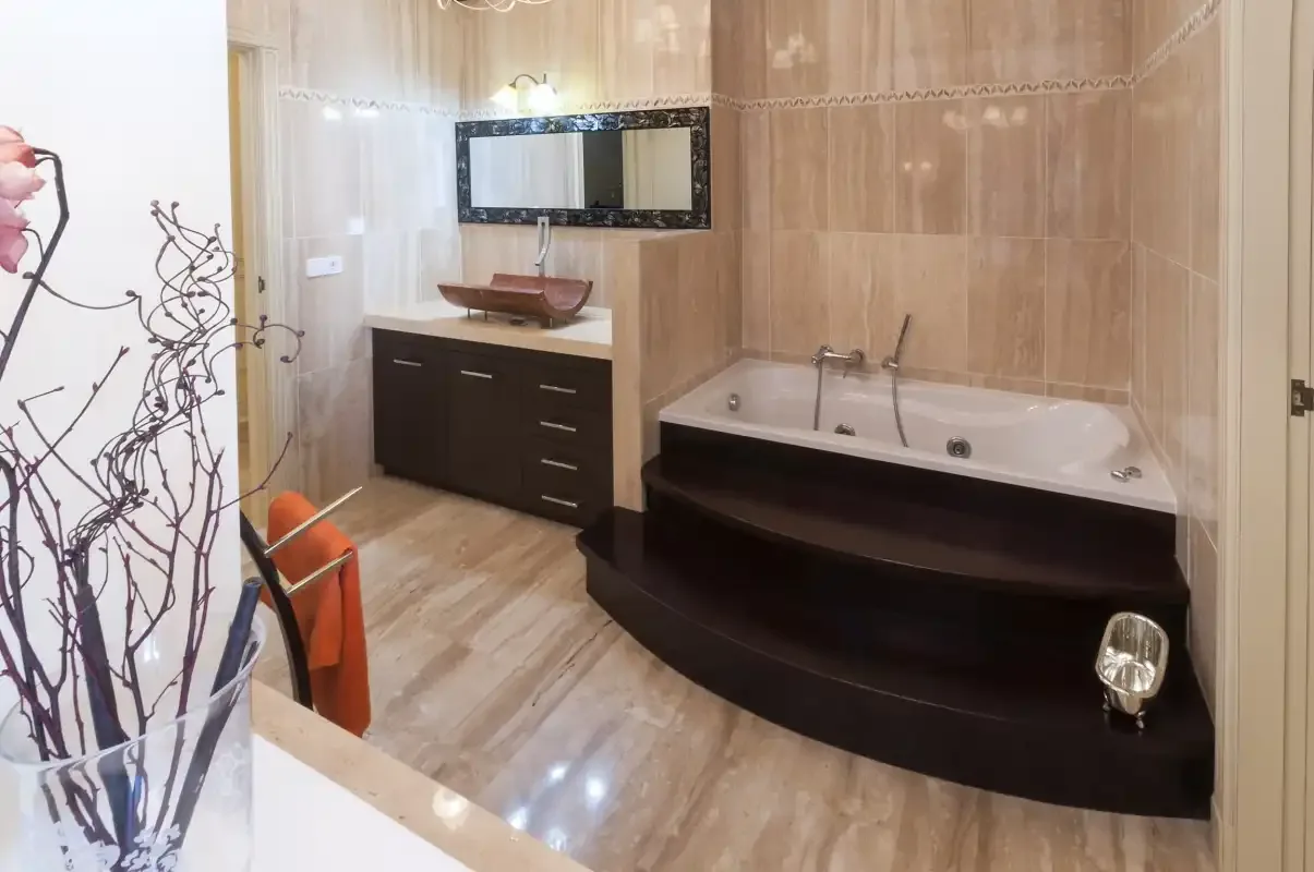 Un baño con bañera y un tocador bajo un espejo.