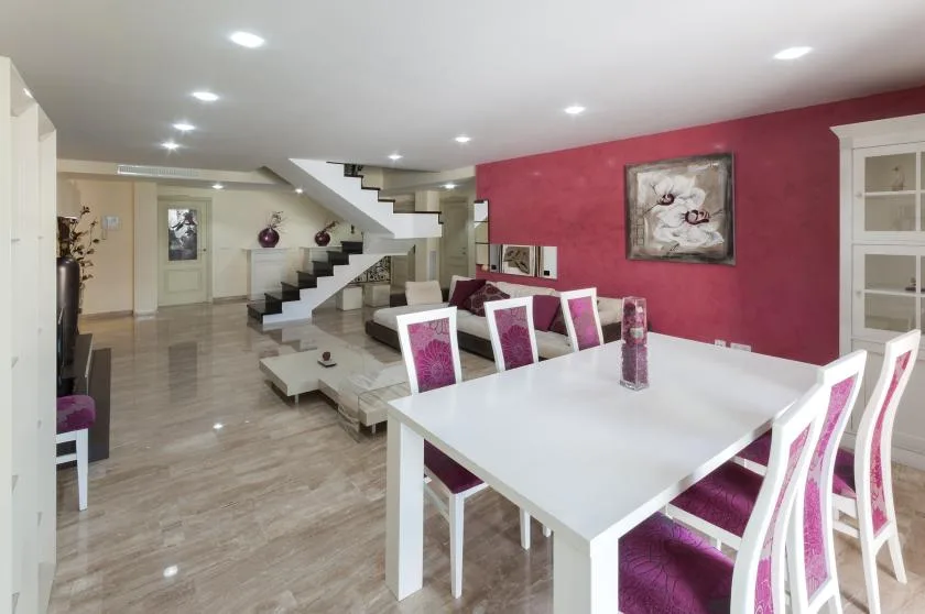 Comedor con una mesa blanca y sillas junto a una escalera.