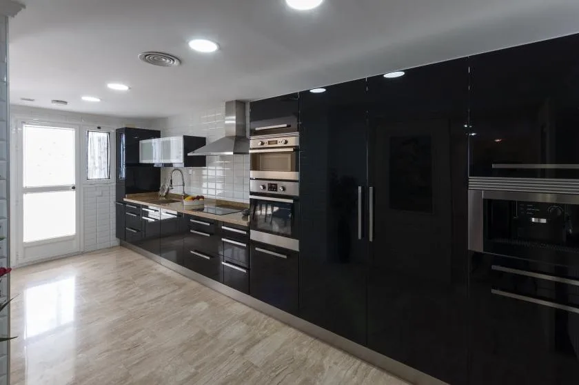 Una cocina moderna con gabinetes oscuros, hornos empotrados y un salpicadero claro de azulejos.