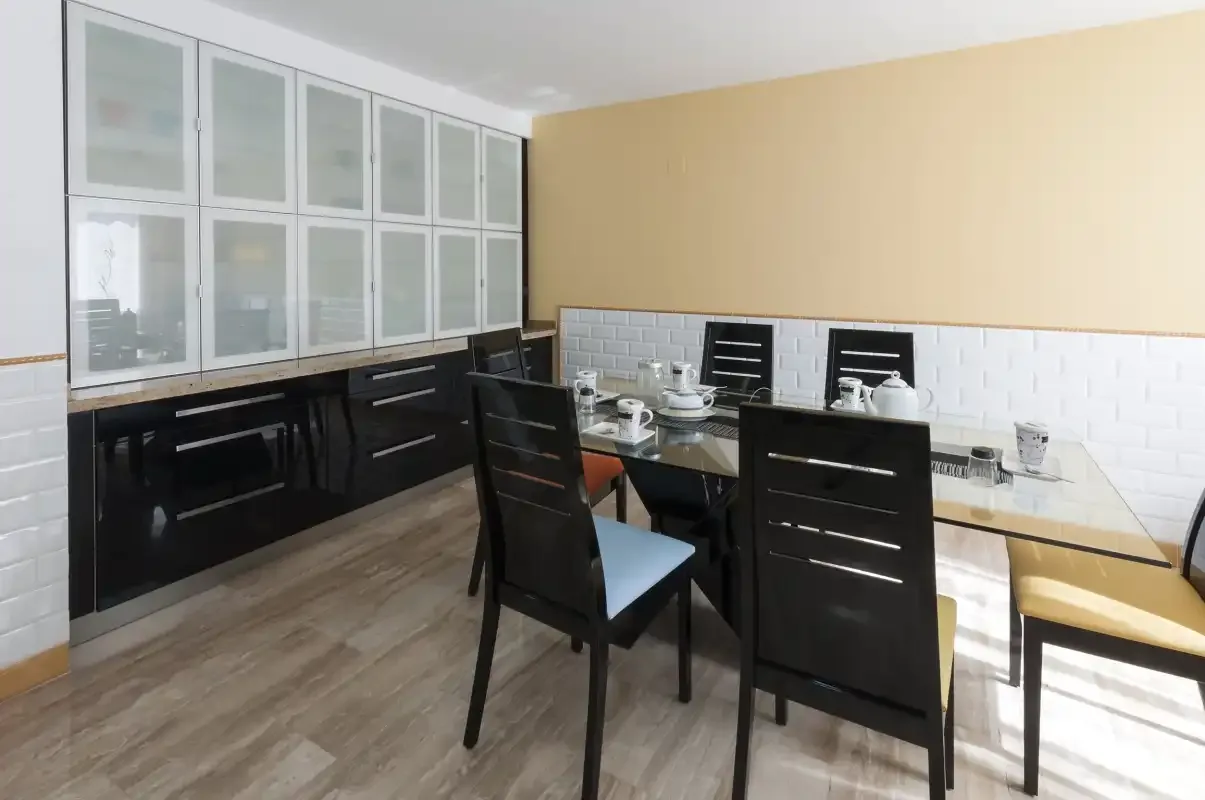 Un comedor con una mesa de vidrio y asientos oscuros.