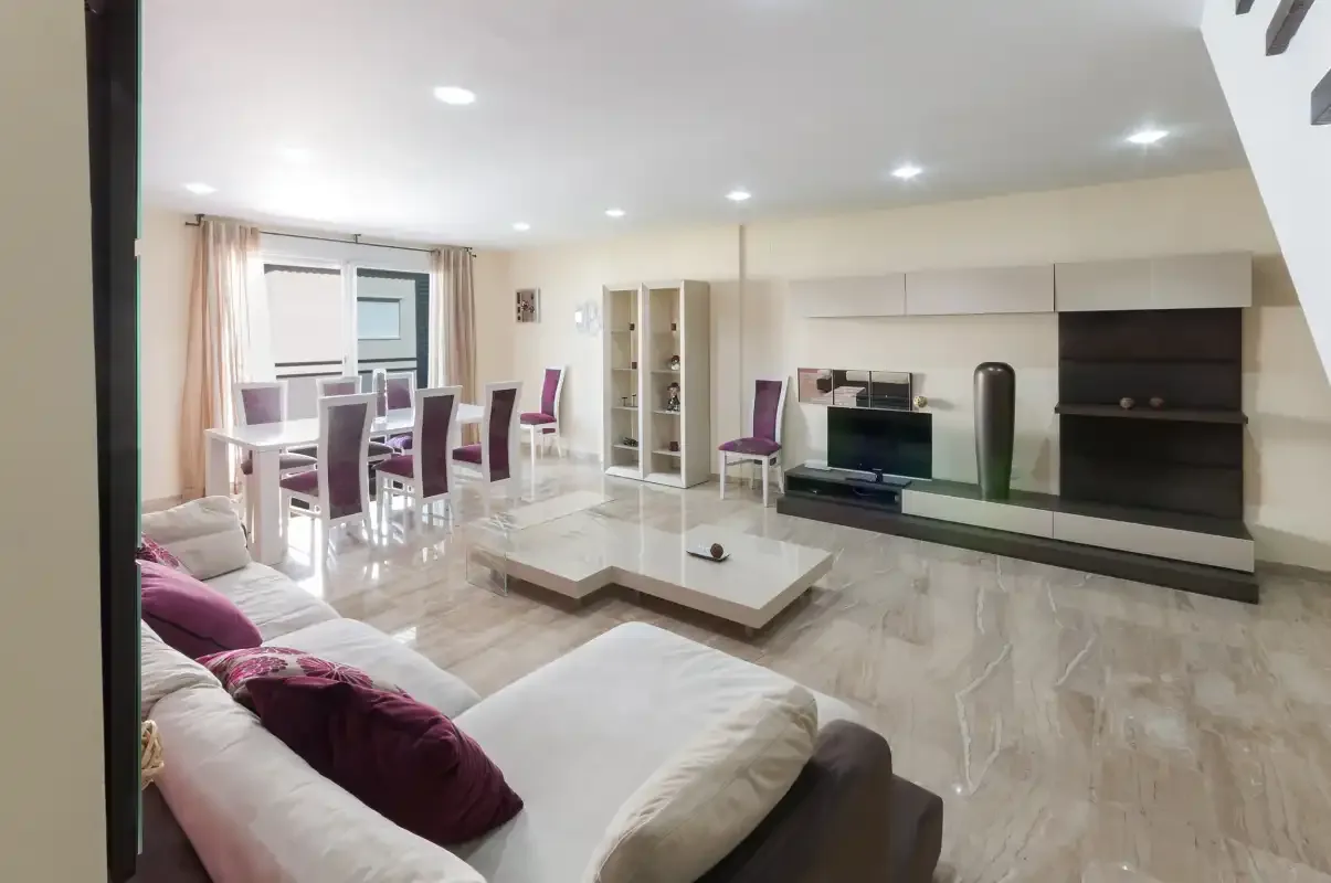 Una sala de estar luminosa con asientos, una mesa de comedor y un televisor.