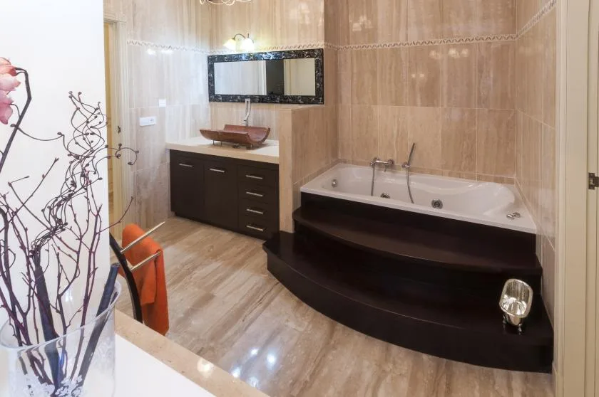 Un baño con bañera, tocador y espejo de pared.