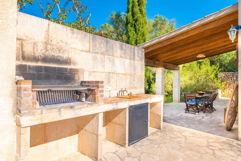 An outdoor cooking area with a built-in grill and a covered dining space.