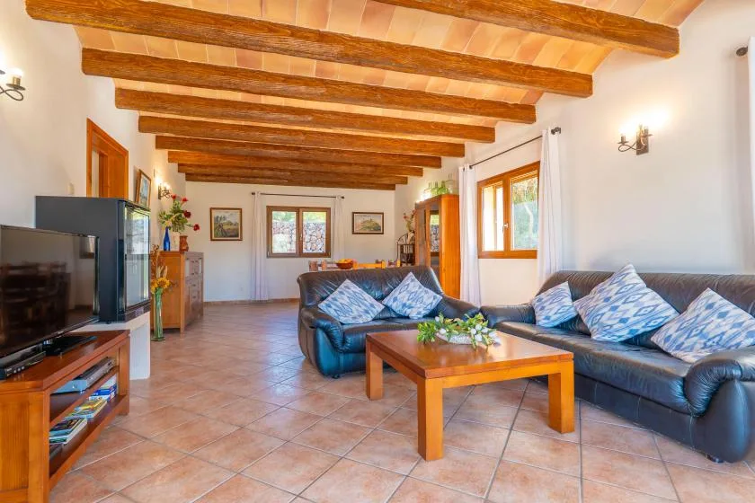 A living room with leather seating, a wooden coffee table, and exposed ceiling beams.