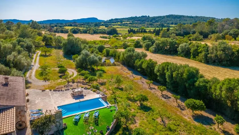 A swimming pool beside a landscaped yard, with fields and wooded hills beyond.