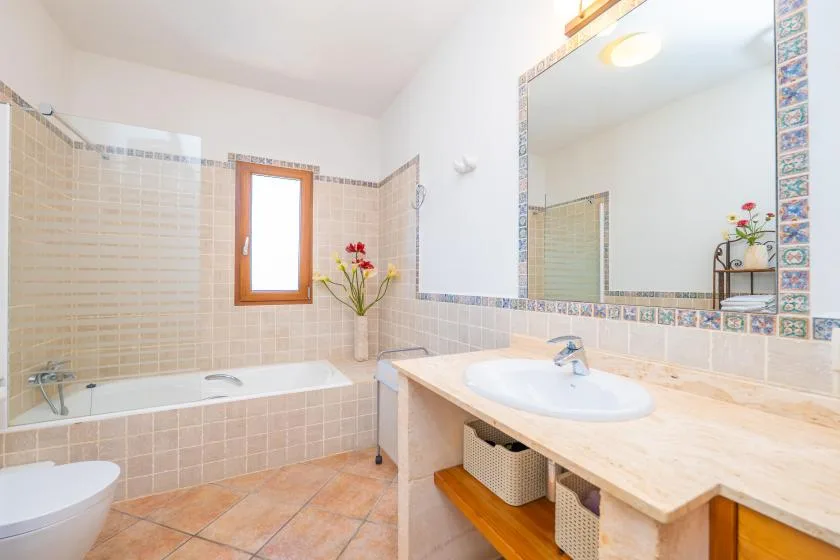 A tiled bathroom with a bathtub, a large mirror, and a sink.
