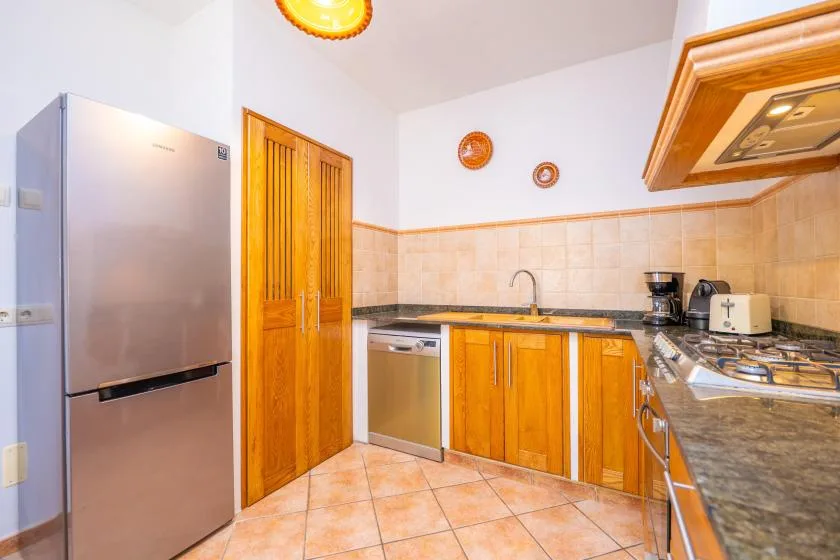 A bright kitchen with wooden cabinets, a refrigerator, and a countertop.