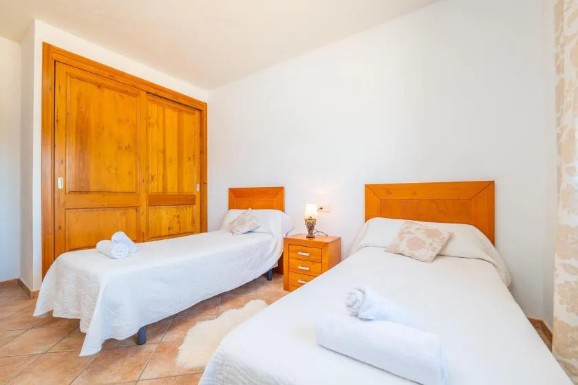 A bedroom with two beds and a wooden wardrobe.