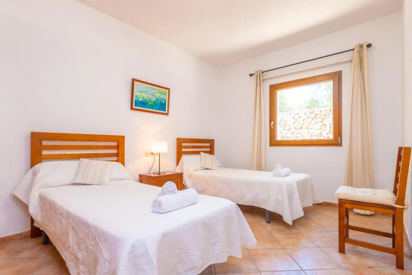 A bedroom with two beds, white linens, and a window with curtains.