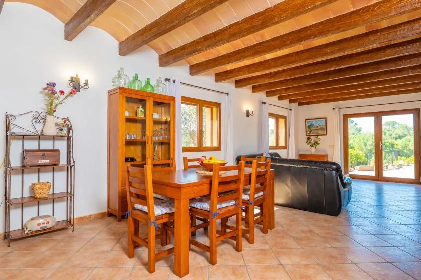 A dining area with a wooden table and chairs beneath exposed ceiling beams.