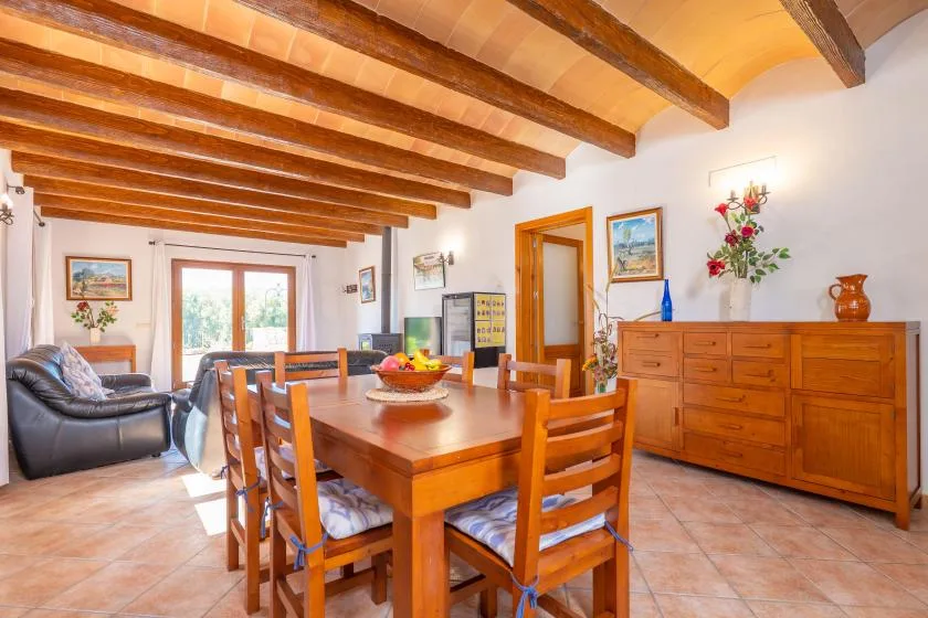 A dining area with a wooden table and chairs beside a living area.