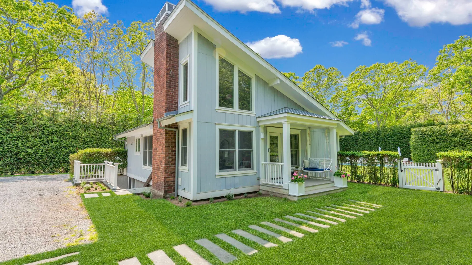 A light-colored house with a covered porch and stepping stones across the lawn.
