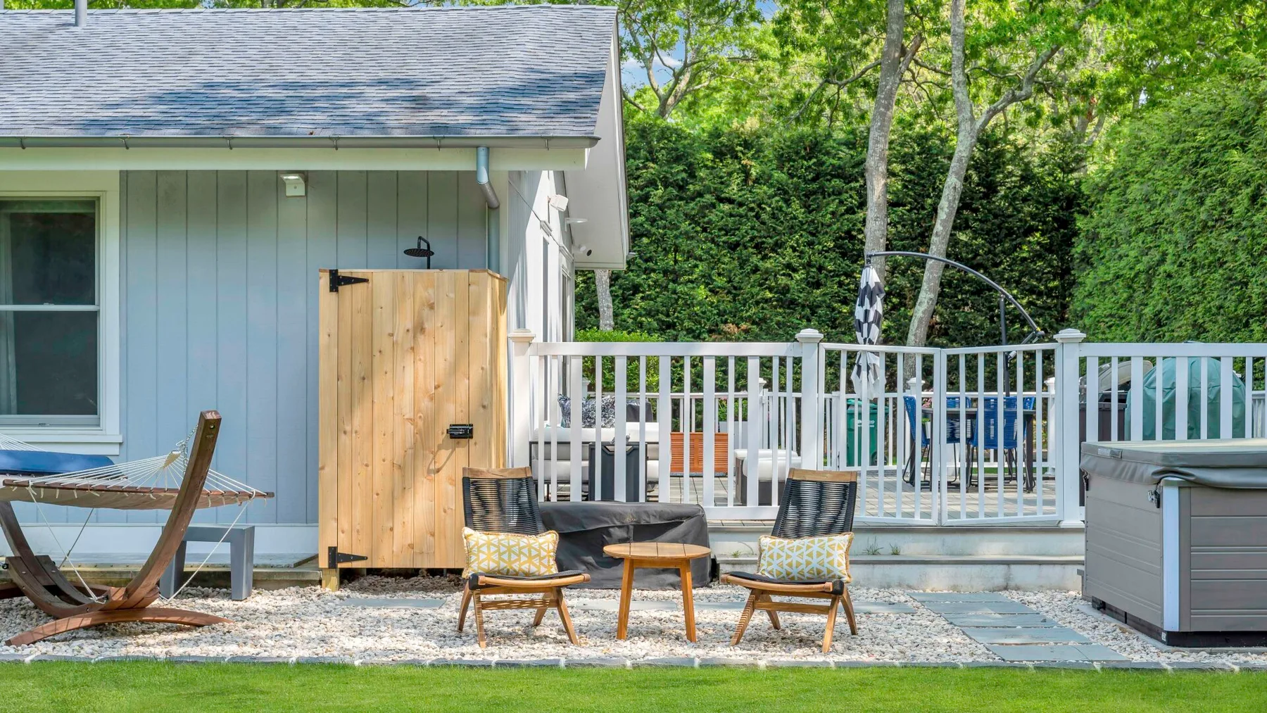 A patio beside a house features outdoor seating and a fenced deck.