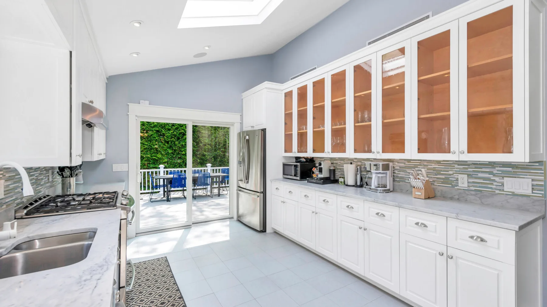 A bright kitchen with white cabinetry and sliding glass doors opening onto a patio.