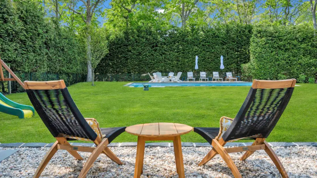 Una zona de estar al aire libre da a un césped verde y una piscina.