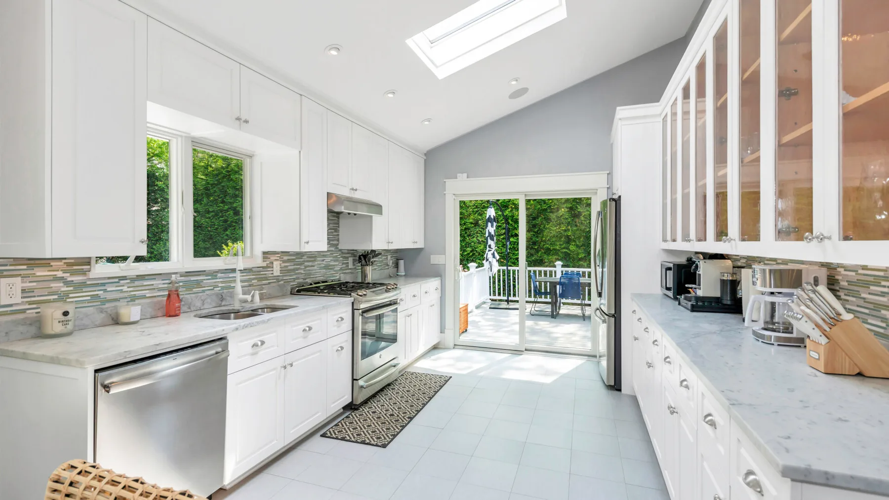 A bright kitchen with white cabinetry and glass doors opening to a deck.