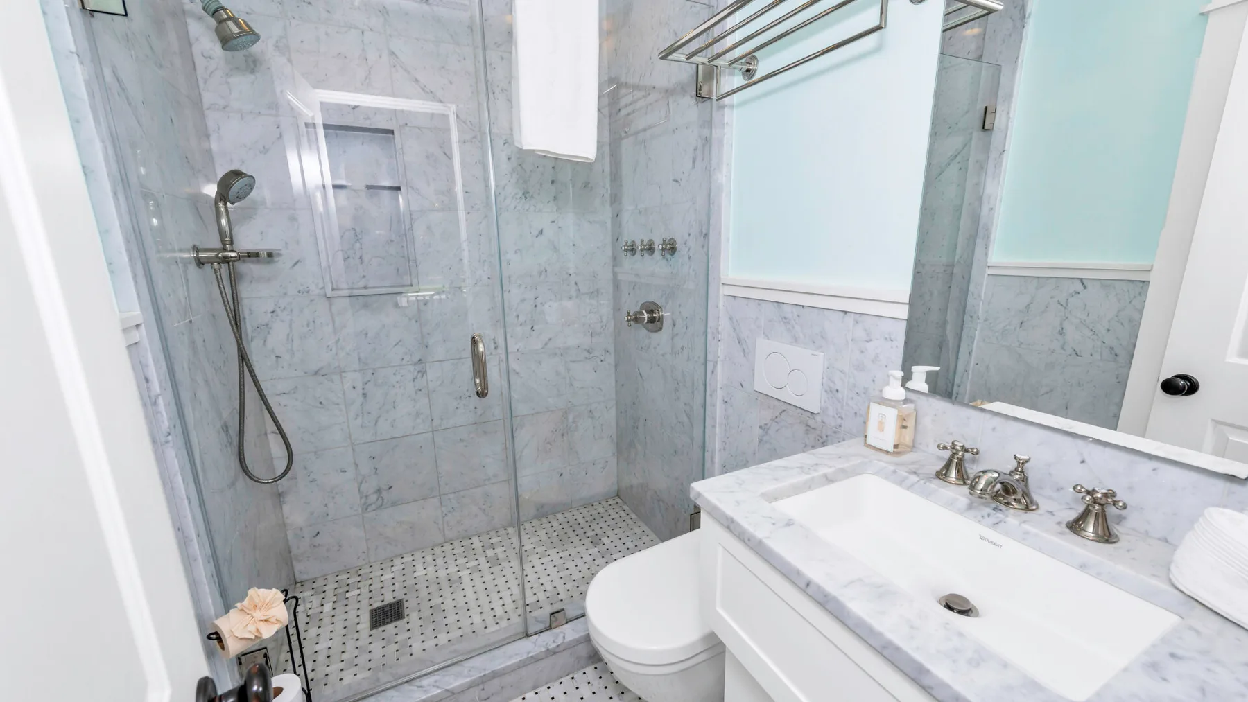 A bathroom with a glass shower, toilet, and white vanity.