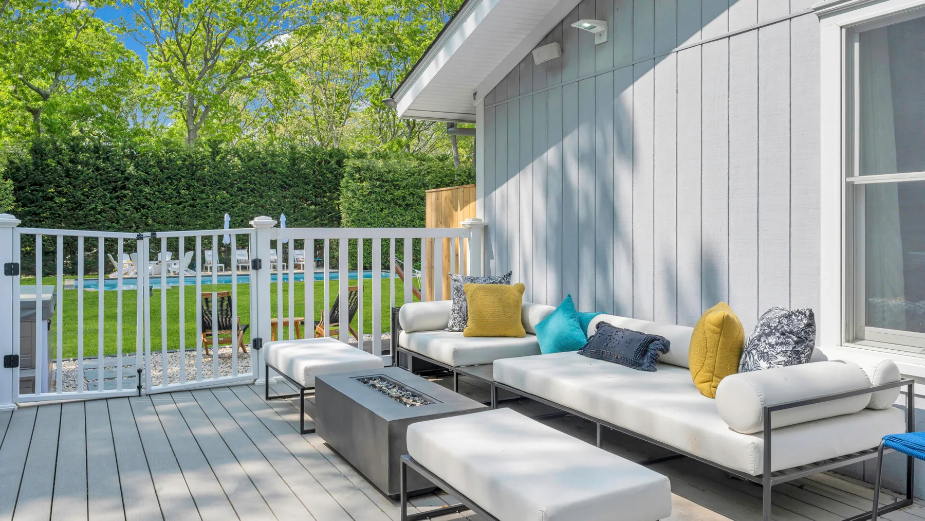 A bright outdoor patio with cushioned seating beside a white railing.