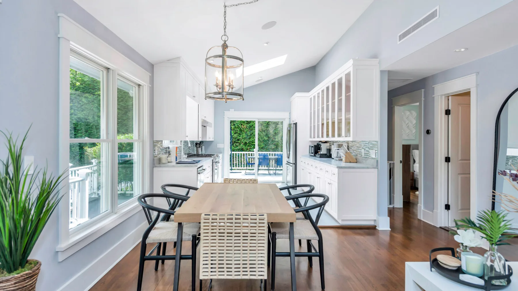 A bright kitchen and dining area with a long table beside large windows.