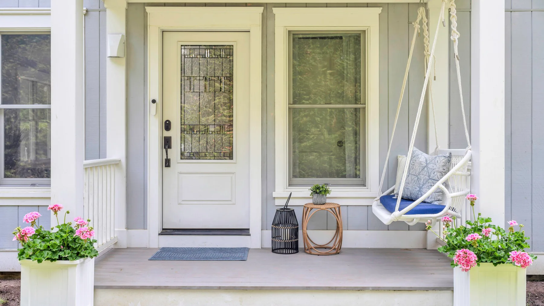 A covered front porch with a door, windows, and a hanging seat.