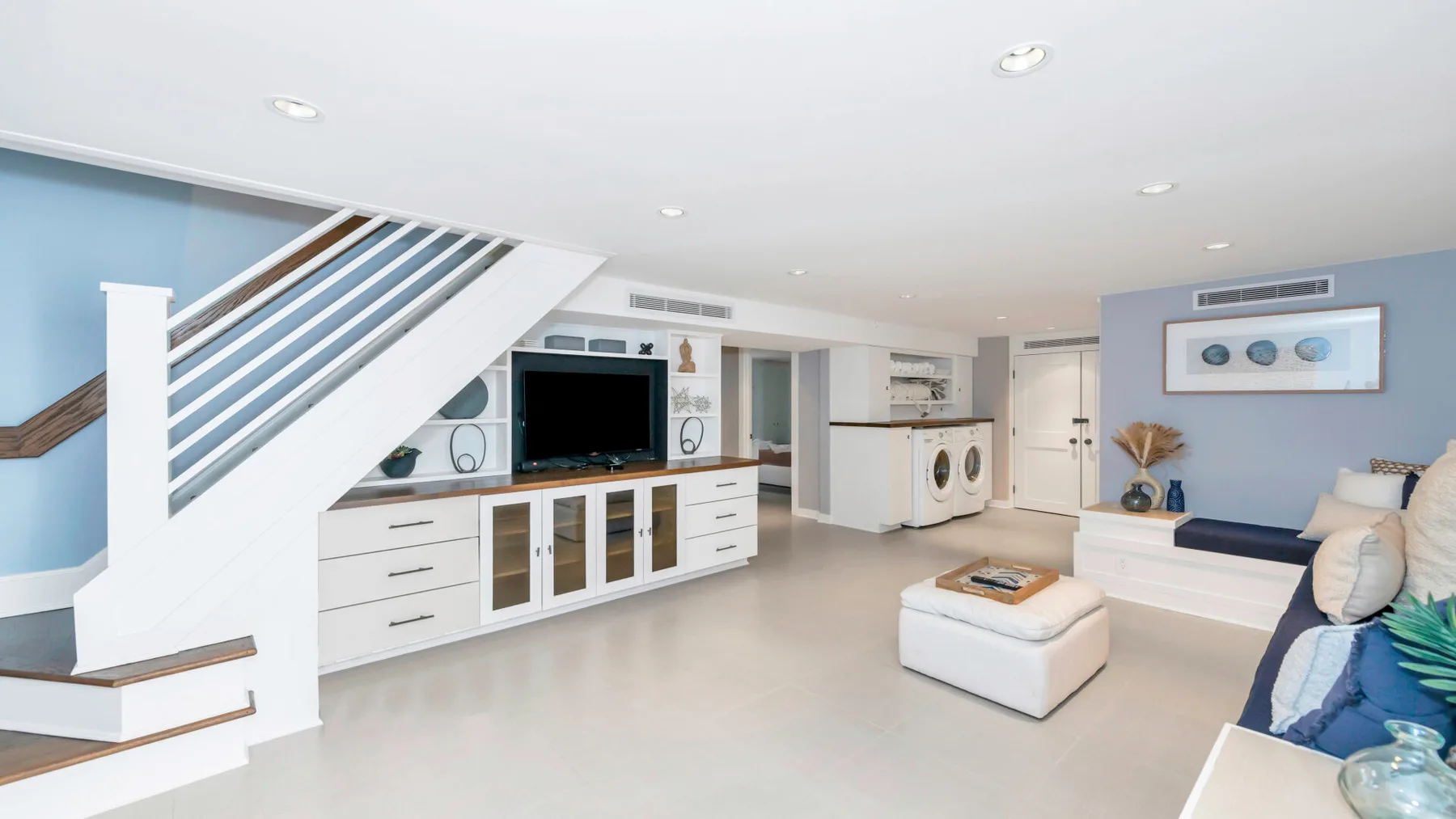 A bright living room with a staircase, television, and seating area.
