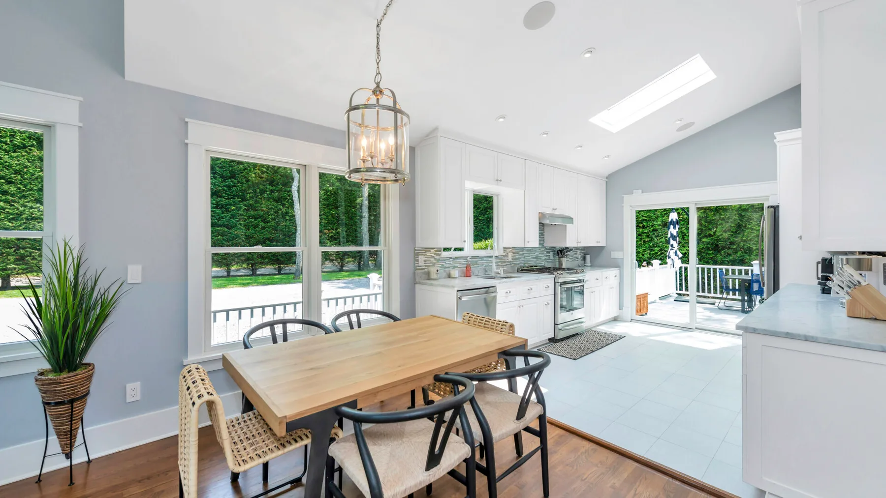 A bright kitchen and dining area with a wooden table and large windows.