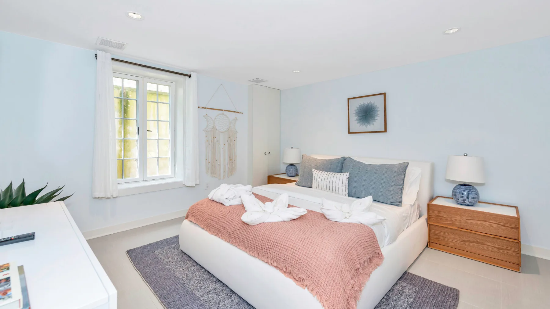 A bright bedroom with a neatly made bed and a large window.