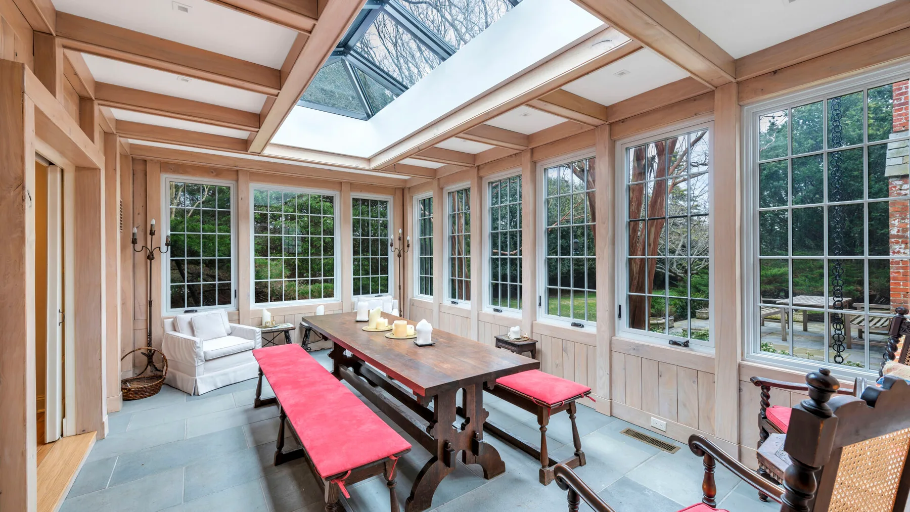 Un luminoso solárium con grandes ventanas y una larga mesa de comedor.