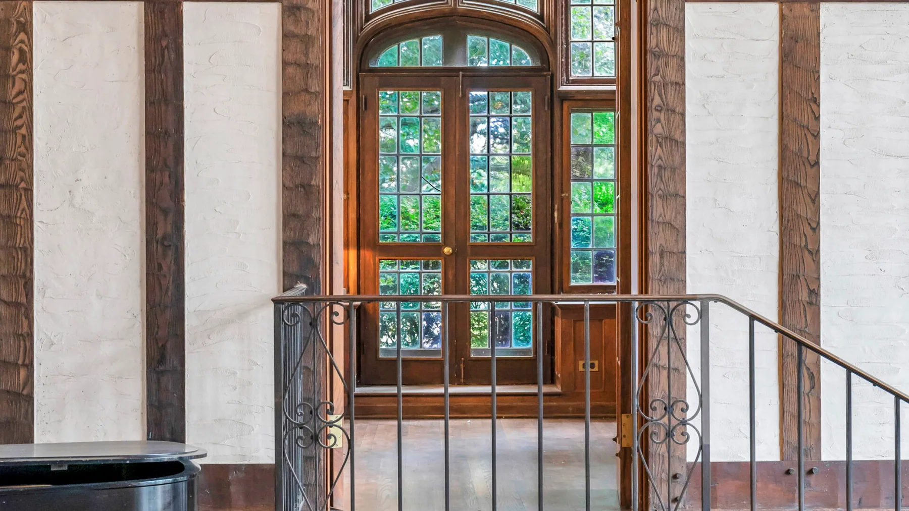 Un rellano interior luminoso con ventanas altas en arco y una barandilla decorativa.