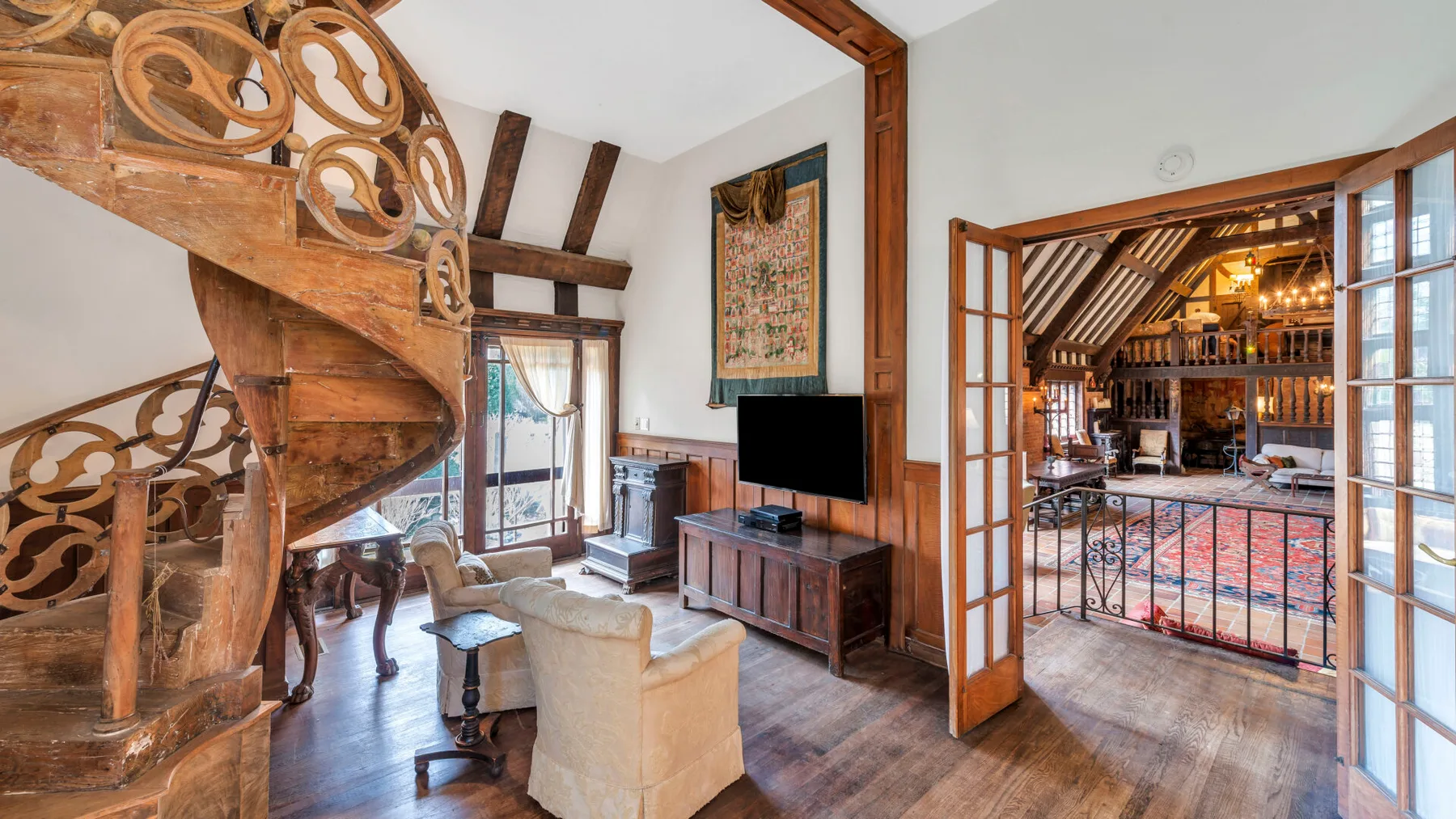 Una sala de estar con una escalera de madera, asientos y una puerta abierta hacia el comedor.