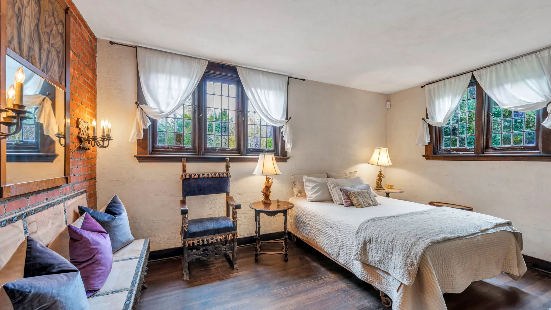 Un dormitorio con una cama, asientos y ventanas con cortinas.