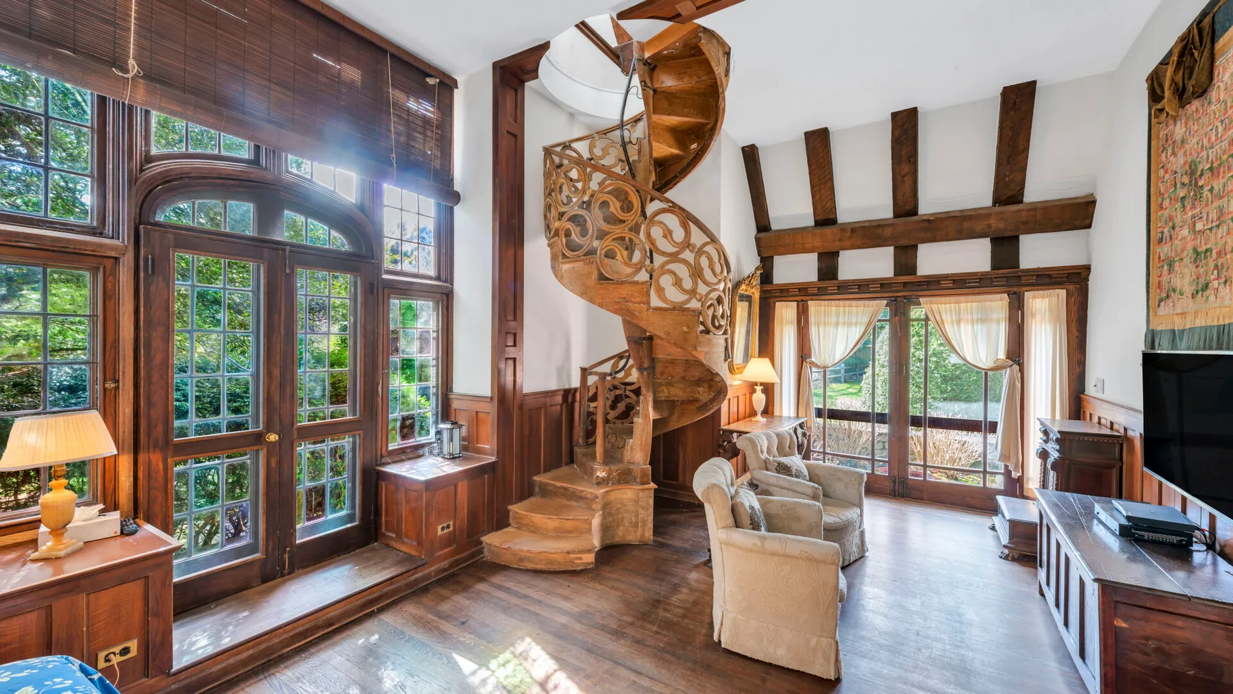 Una sala luminosa con ventanas altas, asientos y una llamativa escalera de caracol.