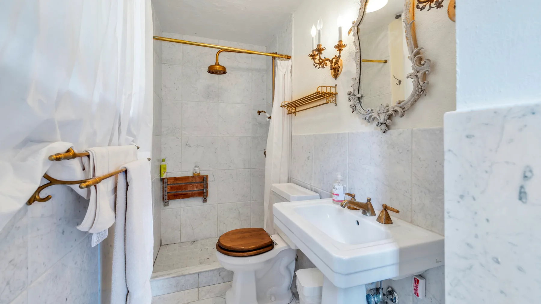 Un baño alicatado con lavabo, inodoro y ducha detrás de una cortina.