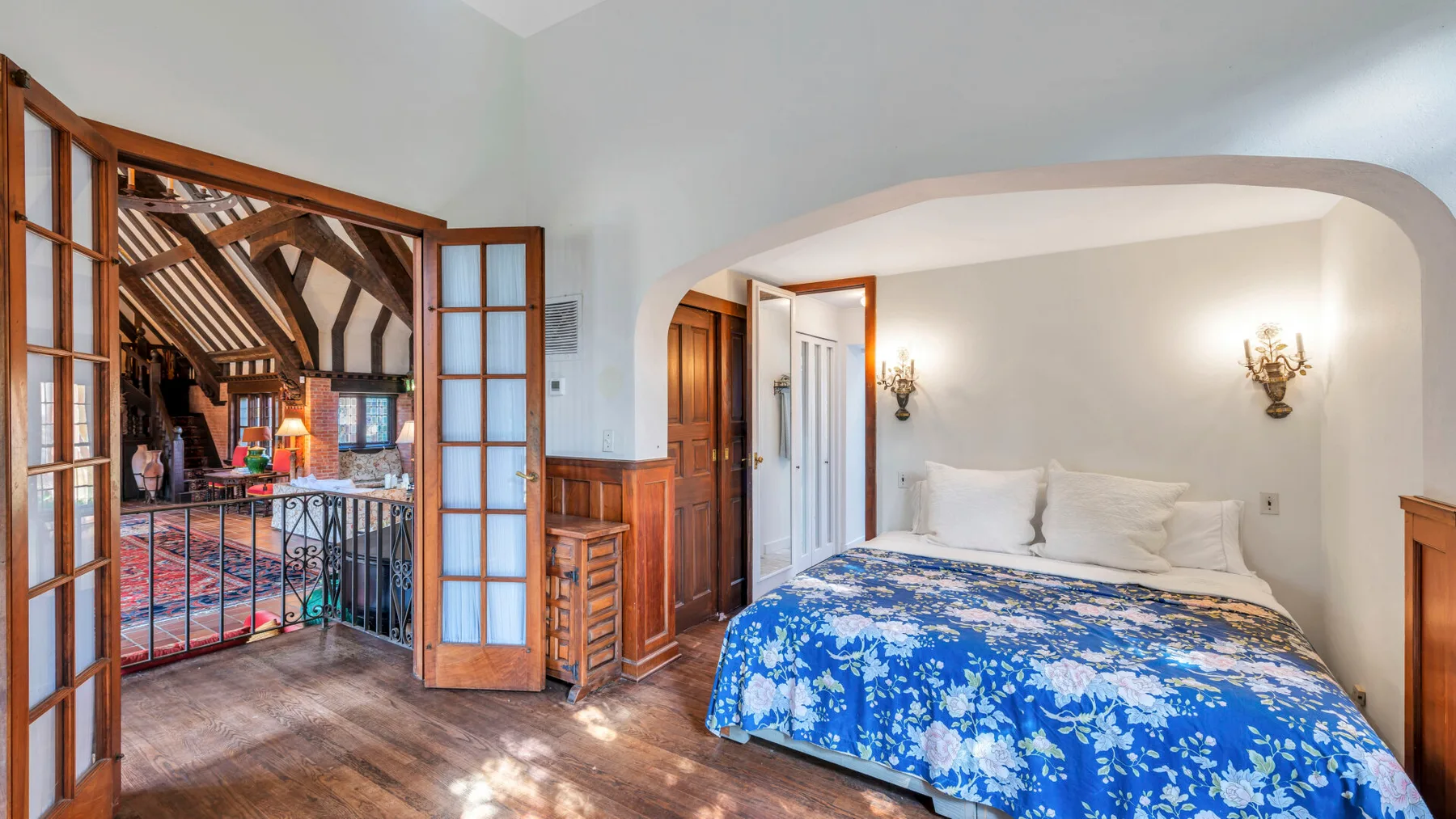 Un dormitorio con una cama cubierta con una colcha floral azul junto a una puerta abierta.