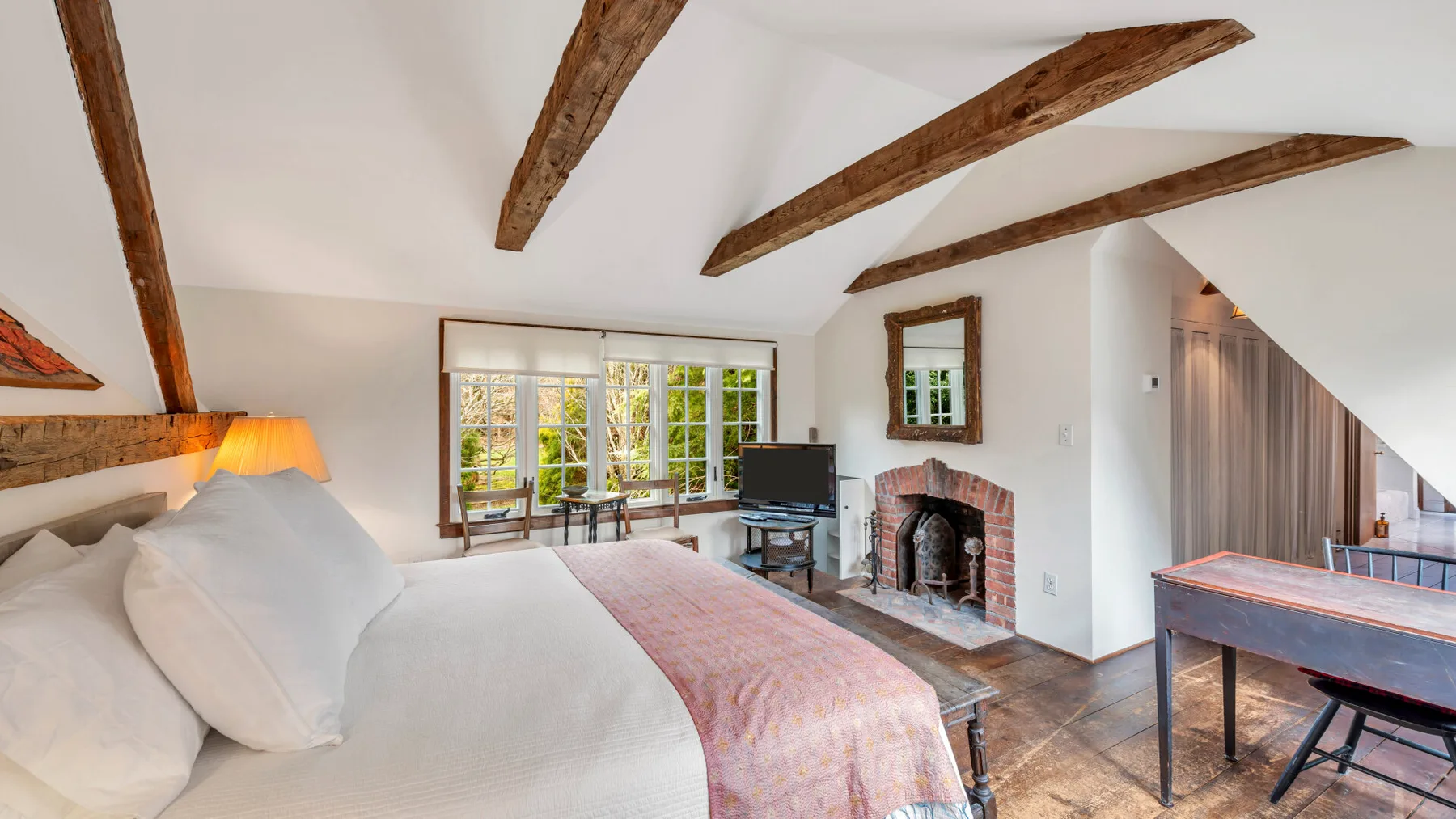 Un dormitorio con una cama grande, vigas de techo a la vista y una chimenea.